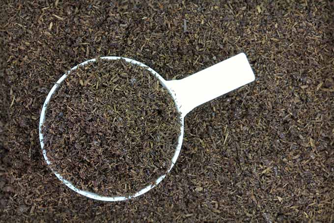 一个近距离的背景图片干燥的蠕虫铸件与一个小的白色塑料勺。