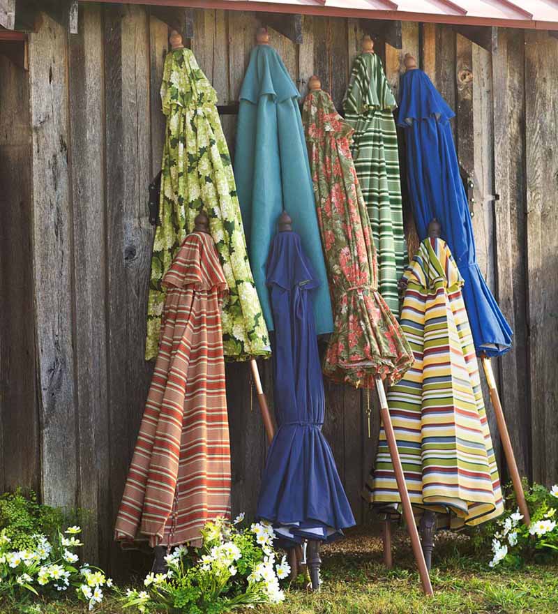 犁土经典市场的各种风格和颜色的雨伞，折叠起来，靠在乡村木栅栏上。