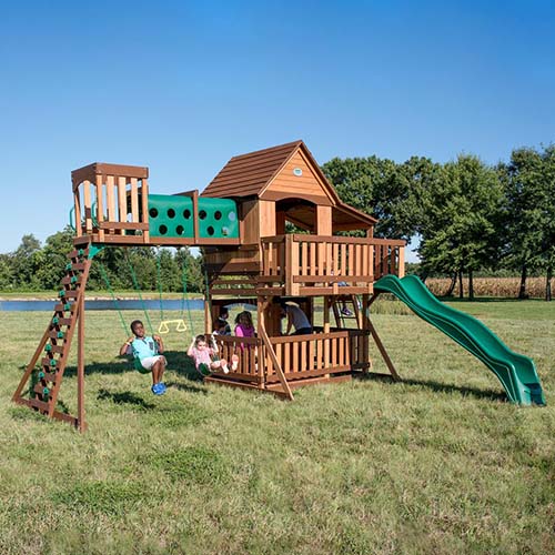 这是后院发现的儿童游乐设施伍德里奇II的照片，设置在草坪上，背景是湖泊和蓝天。