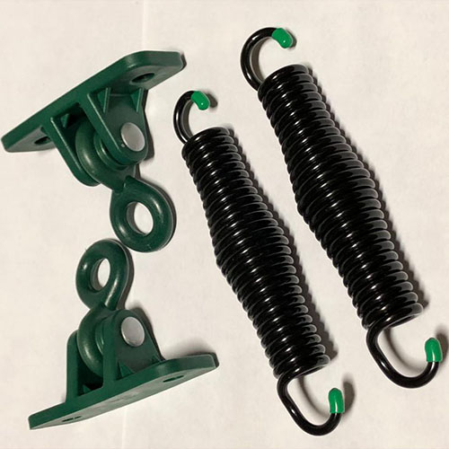 两个黑色金属弹簧和两个绿色金属悬挂支架设置在白色表面的特写。