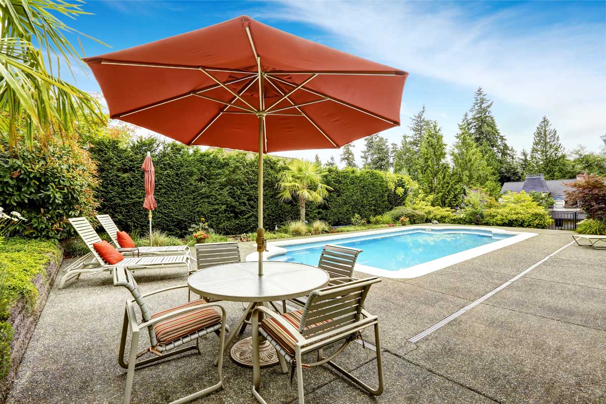 一张桌子和两把椅子上方有一把露台伞，可以俯瞰后院的游泳池。