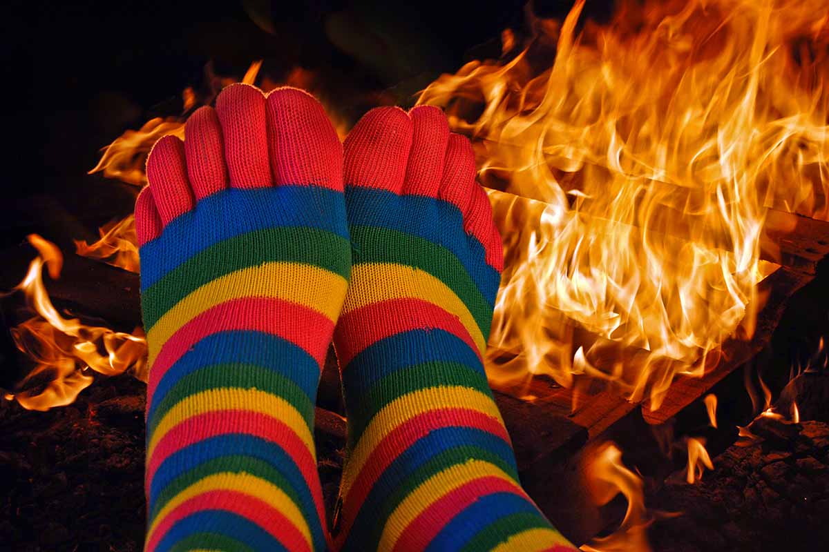 一个近距离的水平图像脚与彩色袜子暖在一个大的户外火前。